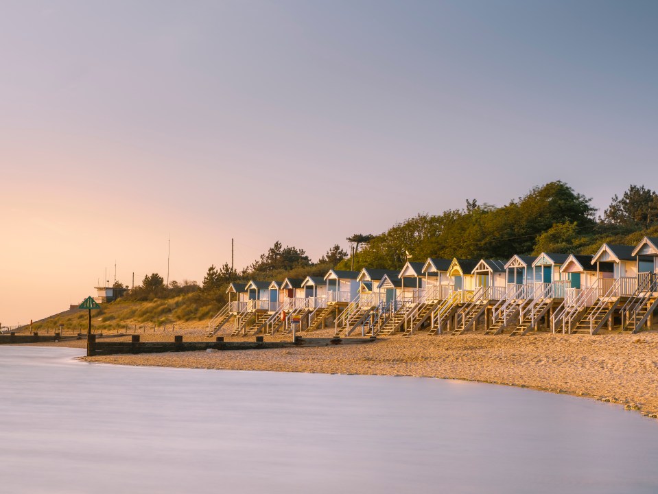 Beach huts on a sandy beach at low tide.