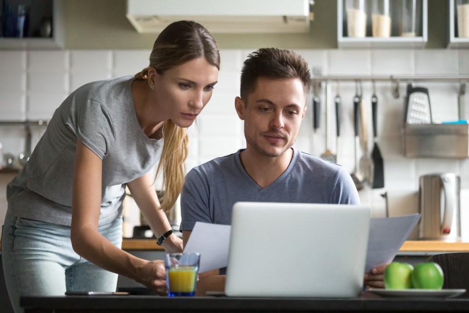 Young couple reviewing documents at a laptop.