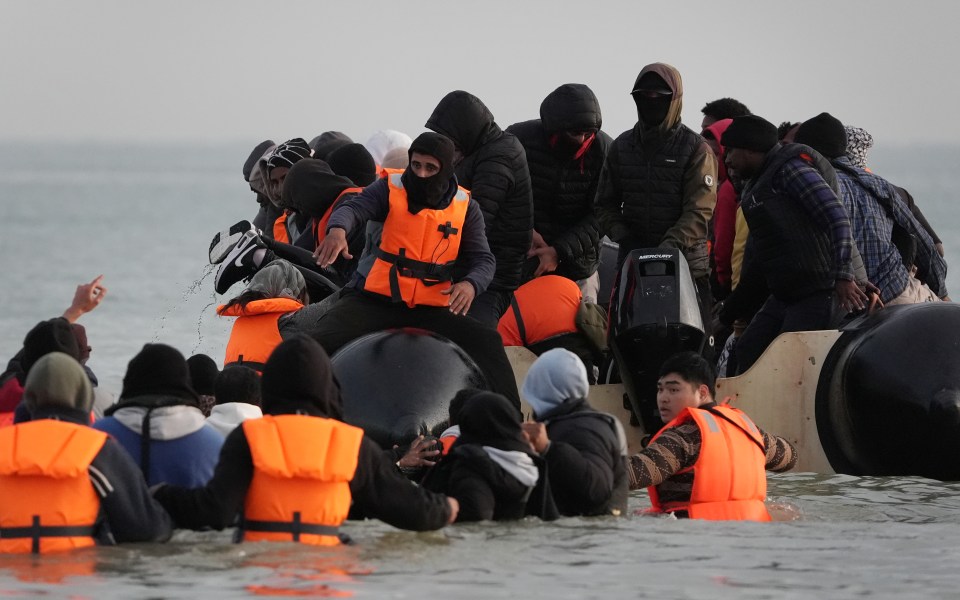 Migrants wading into the sea to board a small boat.
