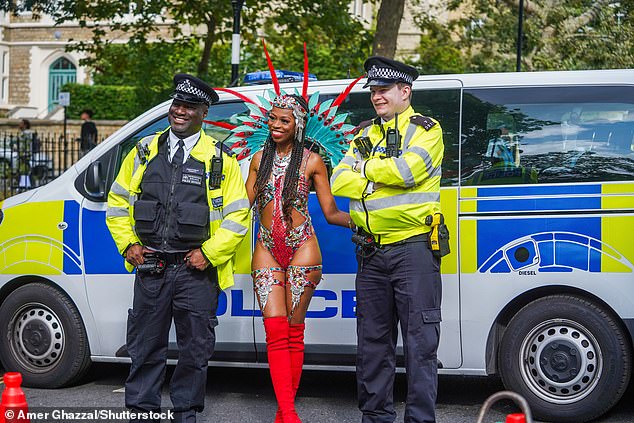 A Samba dancer in feathered costume poses with police officers ahead of the carnival parade at Notting Hill last year