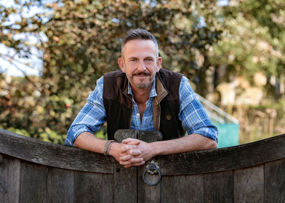 Man leaning on a wooden gate.