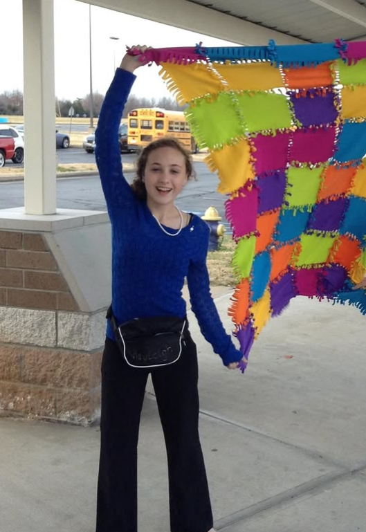Girl holding a colorful patchwork blanket.