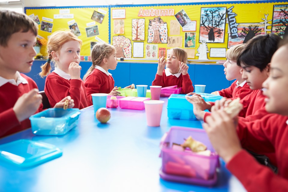 Schoolchildren eating lunch at a table.
