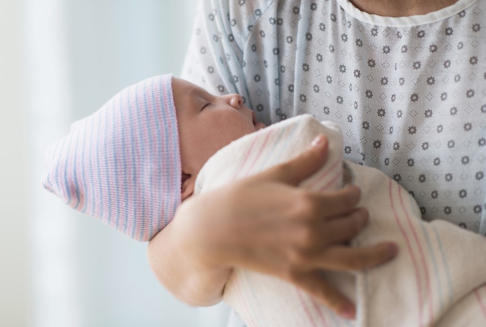 Mother holding newborn baby in hospital.
