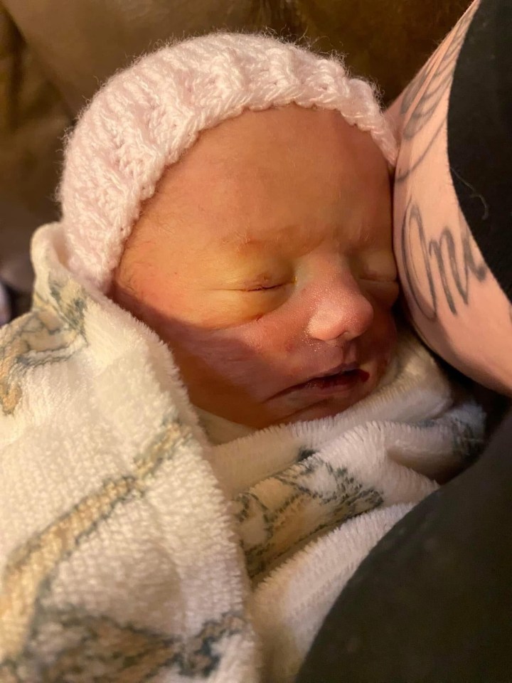 Sleeping newborn baby nestled against a person's shoulder.