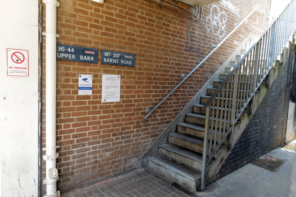 Exterior brick stairway with signage indicating street names and no smoking policy.