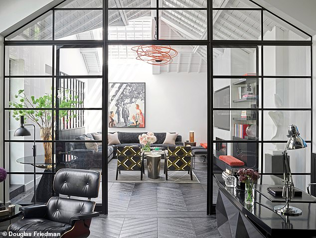 A view of the living room from the study, framed by an eye-catching glasshouse structure. The abstract ceiling light is by Hervé van der Straeten, and the painting above the sofa is by Martin Mull.