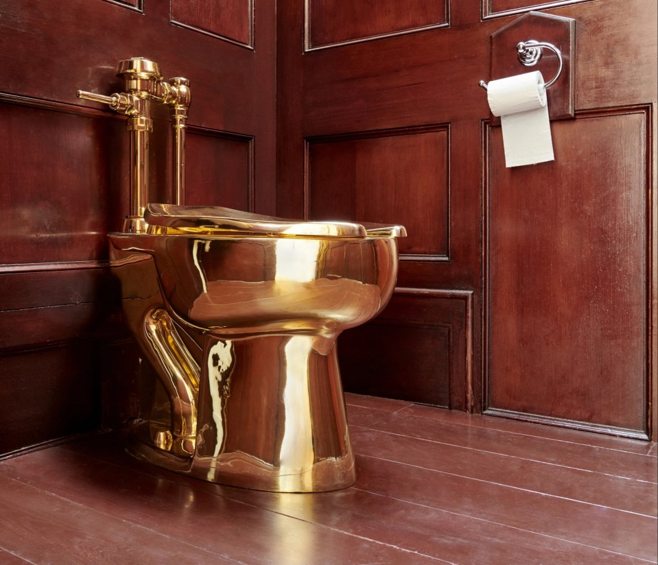 Solid gold toilet sculpture in a bathroom.