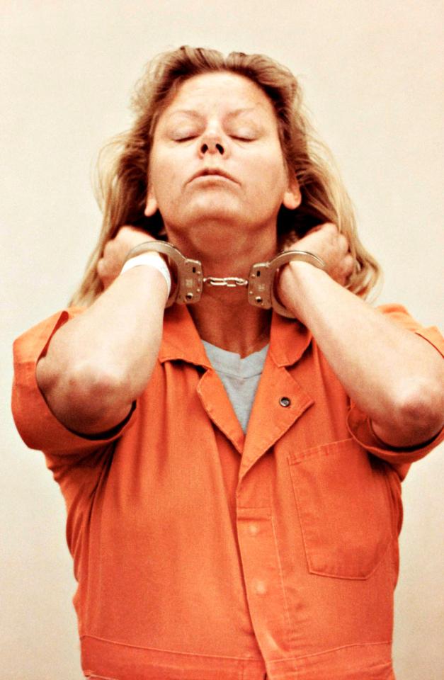 Aileen Wuornos in handcuffs, wearing an orange jumpsuit.