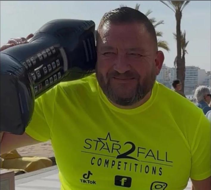 Graham White, a TikTok content creator, holding a large inflatable phone next to his head.