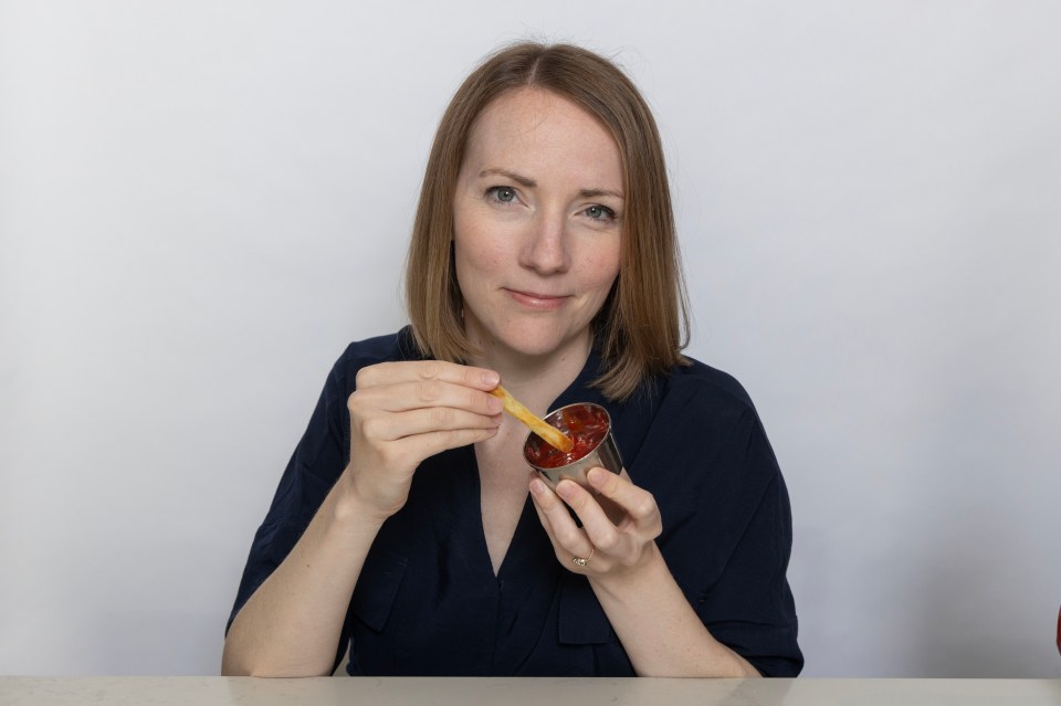 Woman dipping a french fry into ketchup.