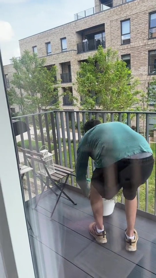 Person tending plants on a balcony.