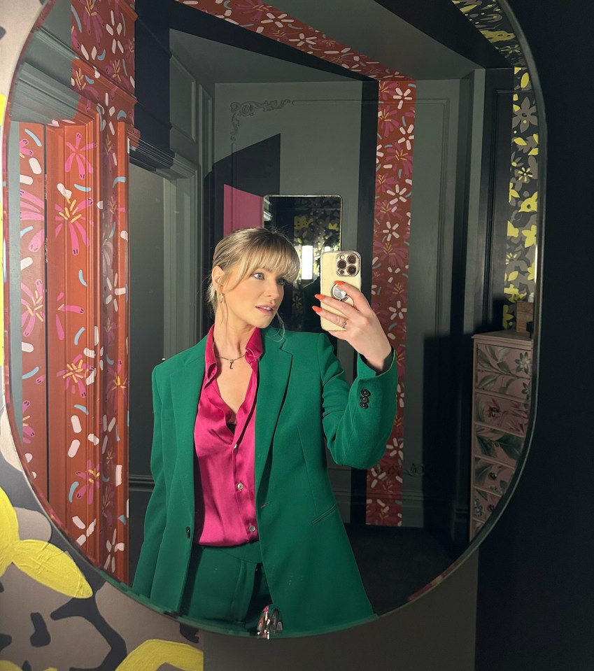 Woman in green suit taking a selfie in a mirror.