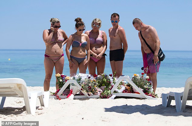 Tourists look at flowers laid at the site of the beach atrocity two days after the attack near the city of Sousse