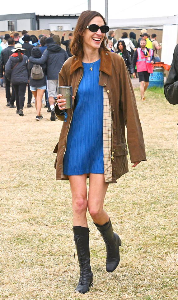 Alexa Chung at a festival wearing a brown jacket and blue dress.