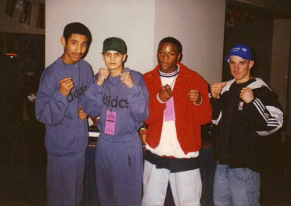 Four young men in sportswear, posing with their fists up.