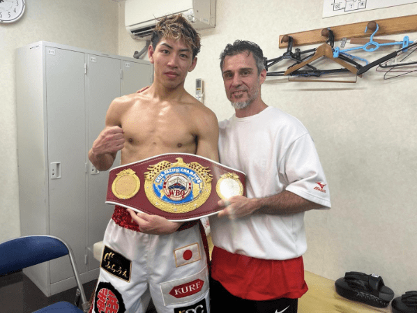 Boxer holding a championship belt with his trainer.