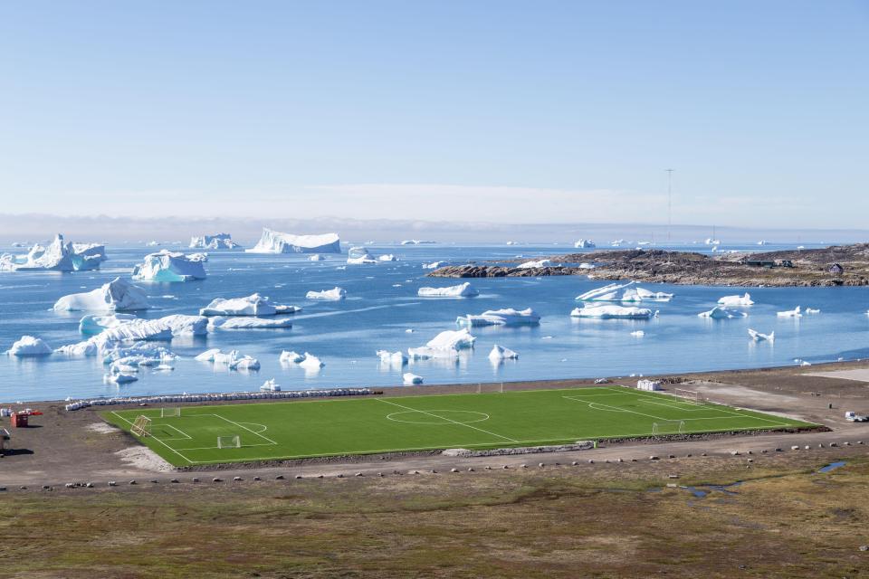 Soccer field in Qeqertarsuaq, Greenland, with icebergs in the background.