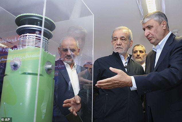 In this photo released by the Iranian Presidency Office, President Masoud Pezeshkian (second right) listens to Head of the Atomic Energy Organization of Iran Mohammad Eslami as he visits an exhibition of Iran's nuclear achievements in Tehran this April