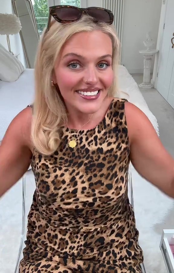 Woman in leopard print dress smiling at camera.