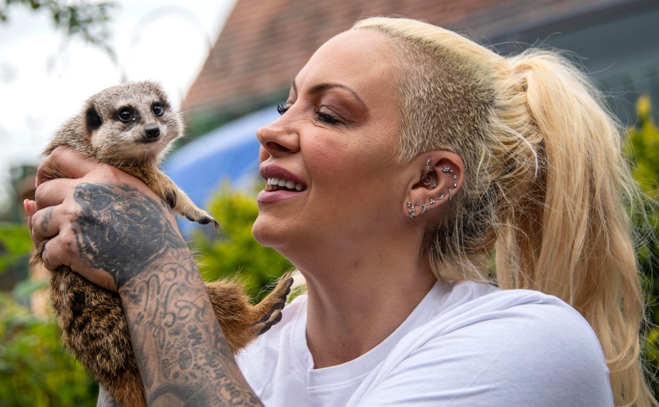 Woman holding a meerkat.