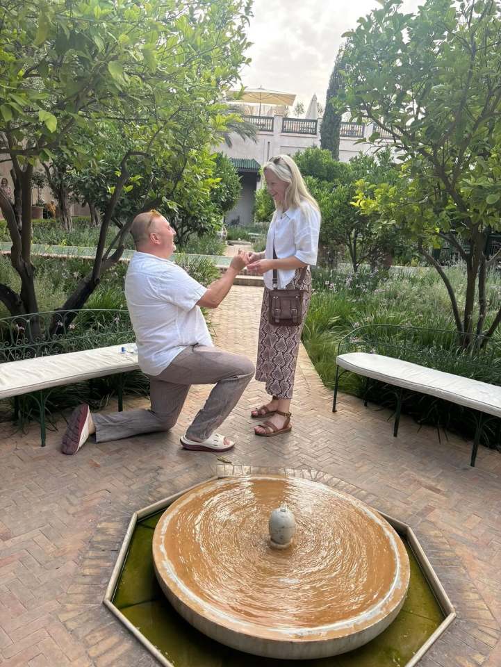 Man proposing to woman in a garden.