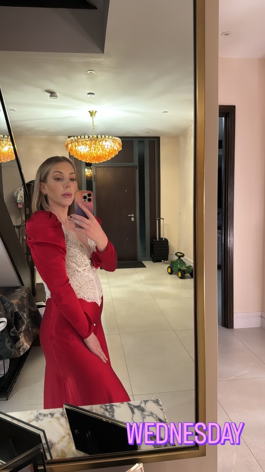 Woman in red dress taking a selfie in a mirror.