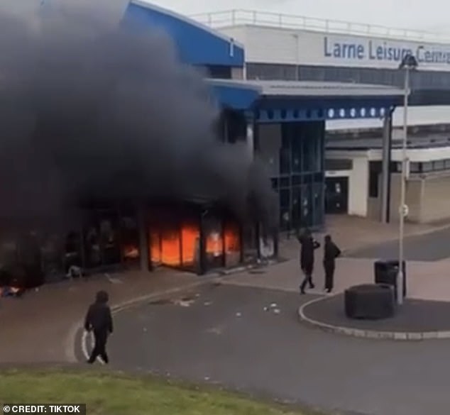 Distressing footage taken outside Larne Leisure Centre tonight shows a group of hooded thugs torching the building, which is understood to have held Romanian immigrants
