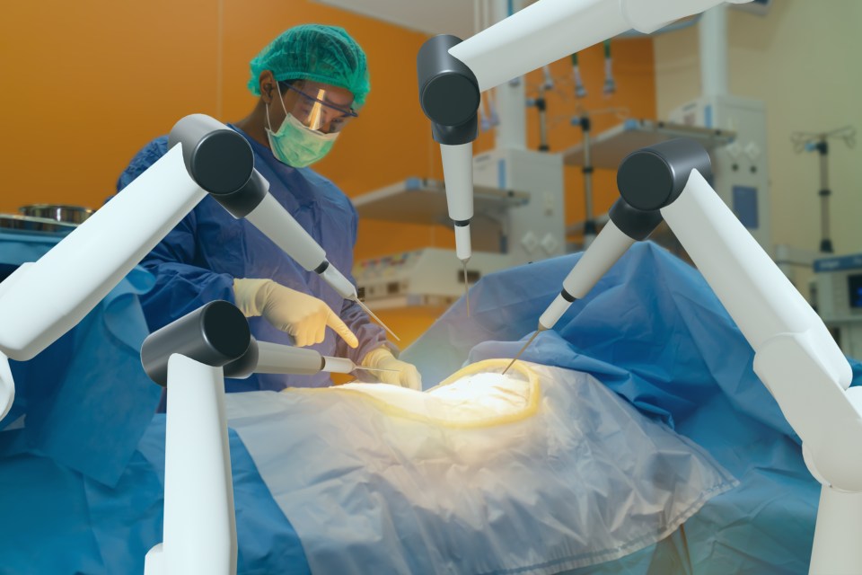 Surgeon using robotic arms during surgery.