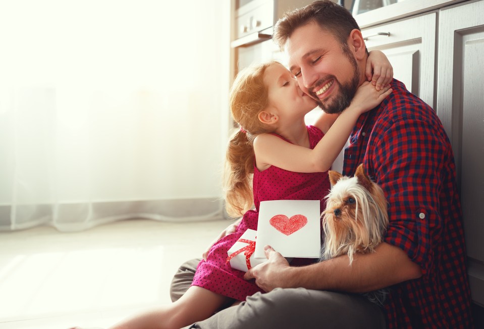 A young girl gives her father a Father's Day card and gift.