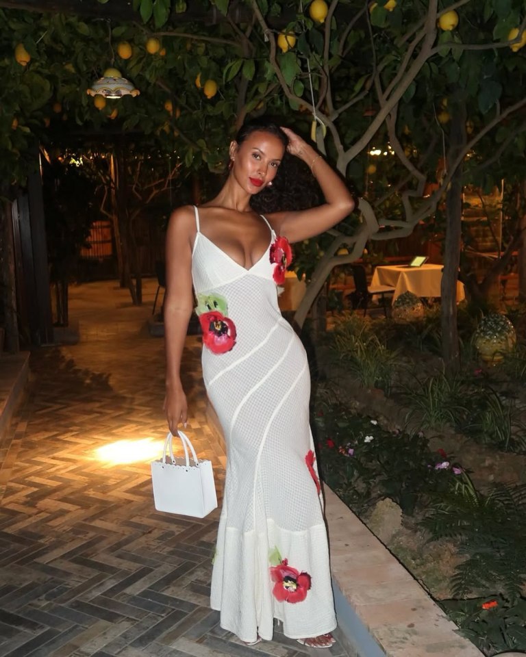 Maya Jama in a white maxi dress with red floral appliqués.