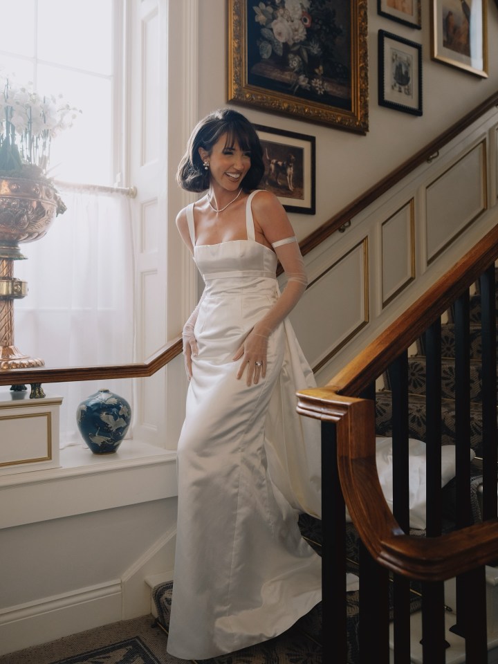 Woman in a white wedding dress descending a staircase.