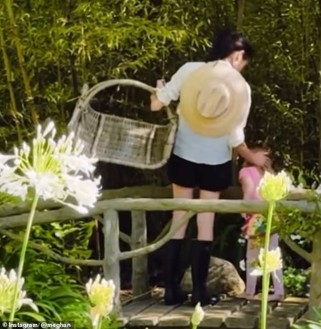 In the sweet clip, Meghan stroked her daughter's hair as they foraged for fresh fruit while stood a bridge (pictured)