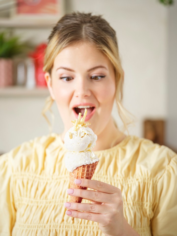 Woman looking surprised at a potato ice cream cone topped with potato sticks.