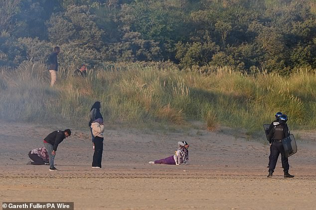 Dozens of migrants battled through teargas grenades on a beach near Calais this morning before setting off for Britain