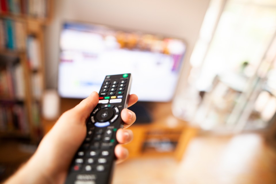 Person using a remote control to change television channels.