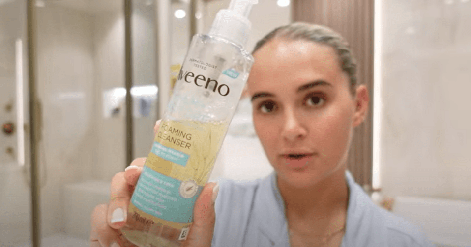 Person holding up Aveeno foaming cleanser.