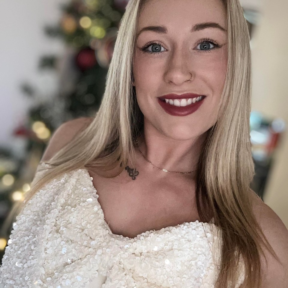 Woman in a sequined top in front of a blurred Christmas tree.