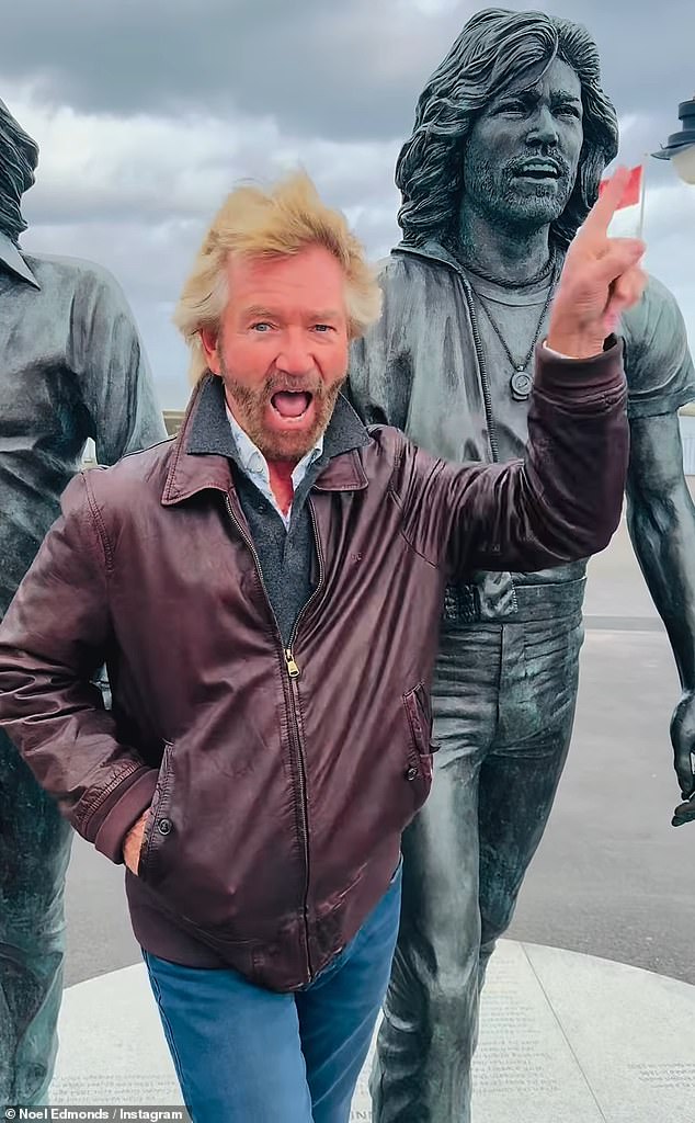 Noel Edmonds, 76, was once again spotted wearing odd shoes as he danced alongside a statute of his doppelgängers the Bee Gees on the Isle of Man on Monday