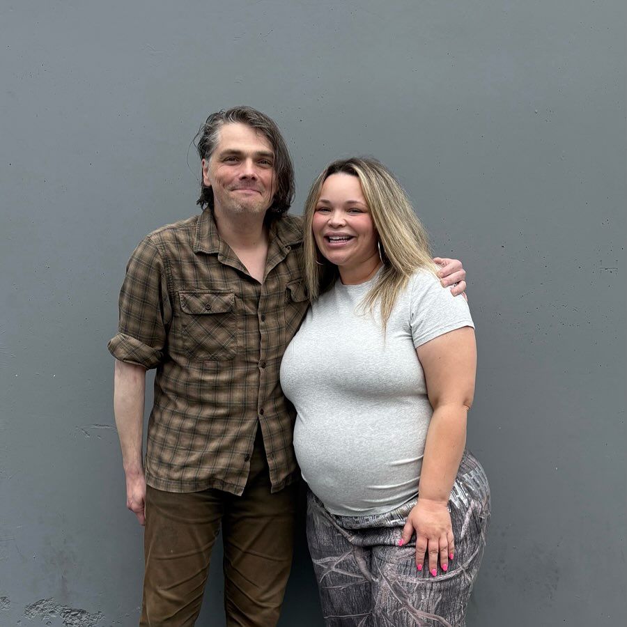 A man and a pregnant woman posing together.