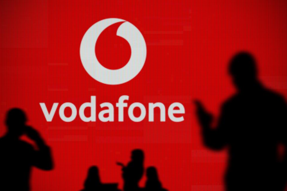 Vodafone logo on a screen with silhouetted people in the foreground.