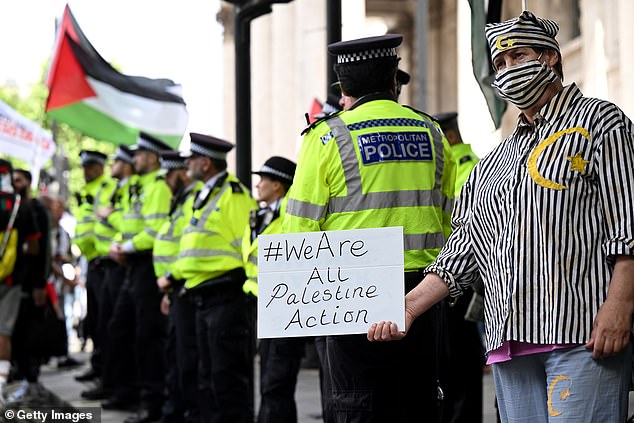 Jailed members of Palestine Action have been successfully spreading the 'intifada' from behind bars, they have brazenly claimed. Pictured: A protester, wearing what appears to be a Holocaust victim outfit, holds a sign reading 'We are all Palestine Action'