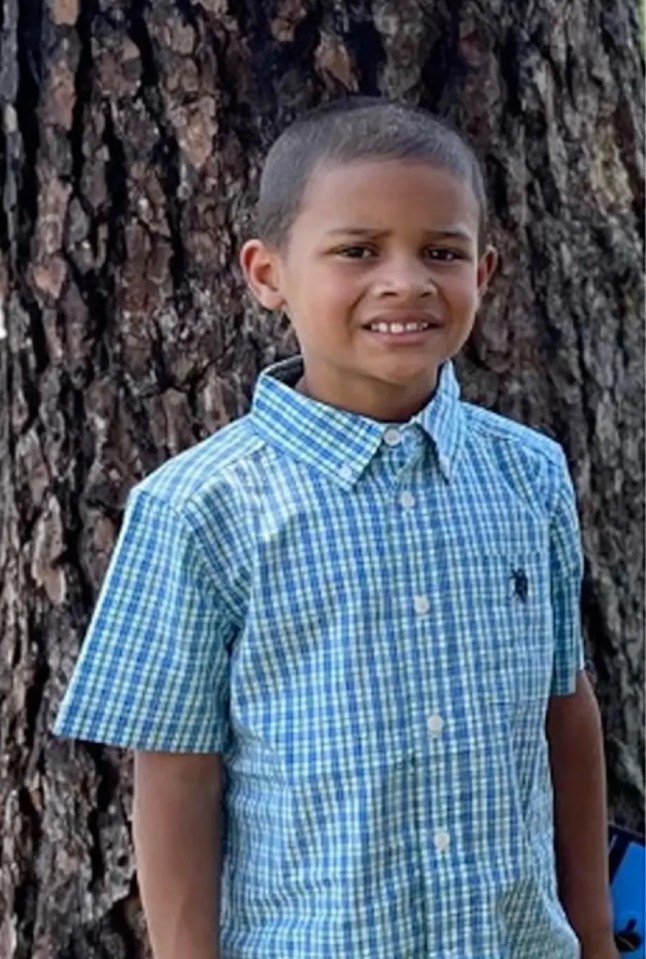 Photo of a young boy in a blue and green checkered shirt.
