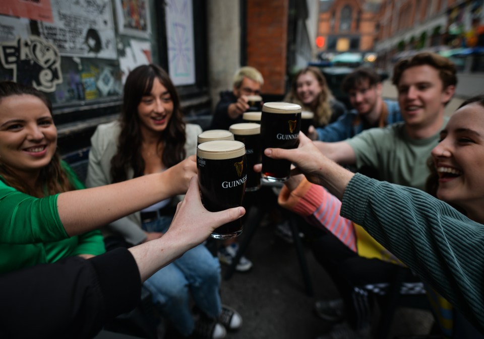Friends toasting with pints of Guinness outside a Dublin pub.