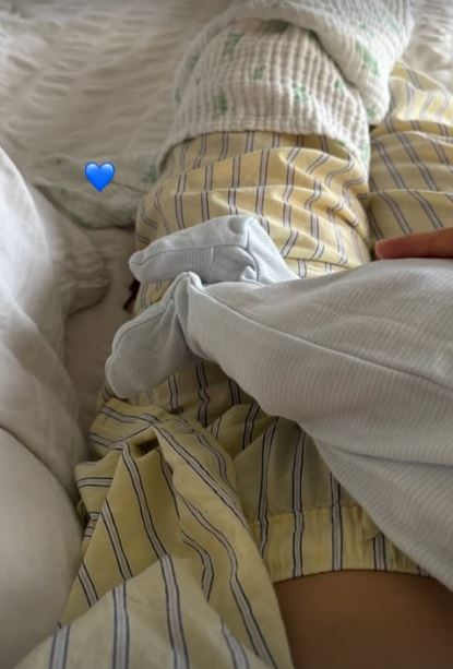 A woman in striped pajamas in a hospital bed with a baby.
