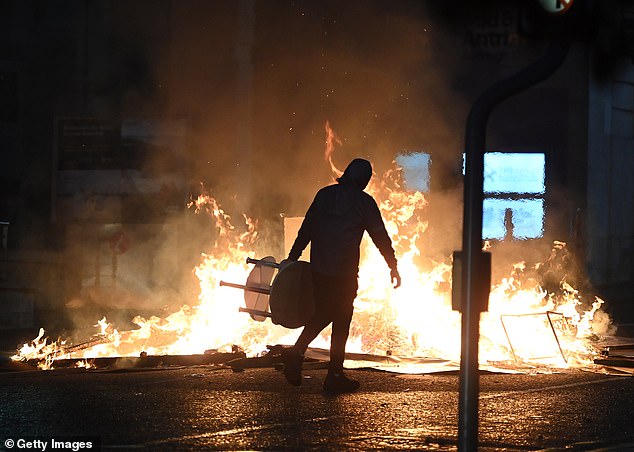 A fire rages as PSNI riot squad officers battled protesters who threw projectiles and set vehicles on fire