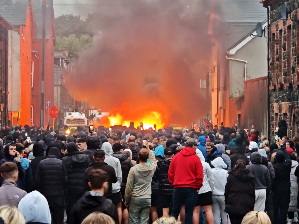 Large crowd watching a fire during a protest.