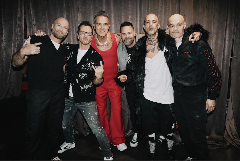 Robbie Williams and the band Five posing together.