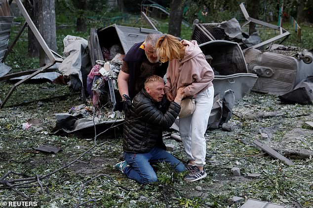 A sobbing father is inconsolable outside a building in Kyiv which collapsed on his son after being struck by a Russian missile