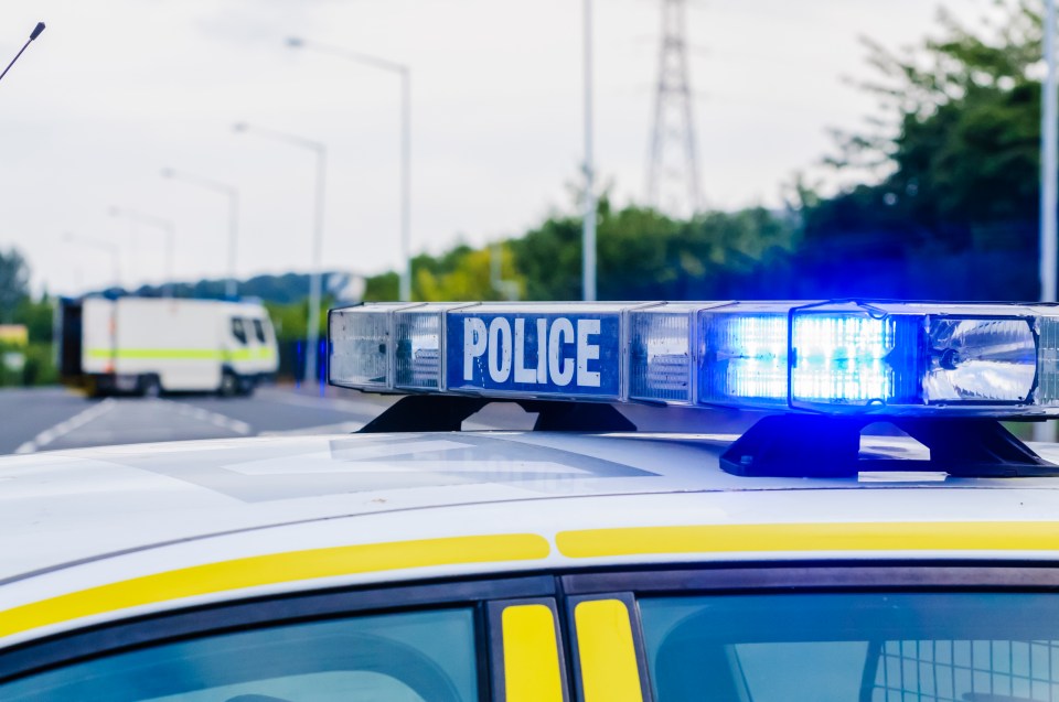 Police car with flashing blue lights at a road closure.